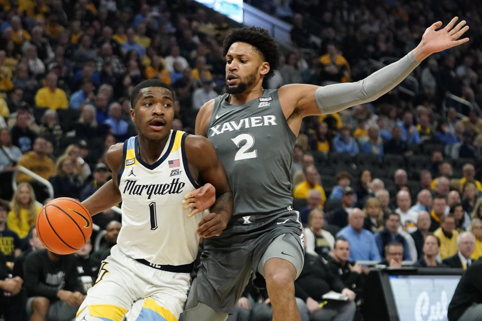 Marquette's Kam Jones (1) drives to the basket against Xavier's Jerome Hunter during the first half of an NCAA college basketball game Wednesday, Feb. 15, 2023, in Milwaukee. (AP Photo/Aaron Gash)