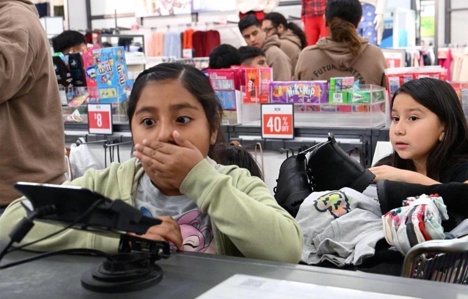 Niños de Live Again Fresno reaccionan mientras la ropa es revisada en las cajas registradoras durante una compra en Old Navy, la mañana del lunes 18 de diciembre de 2023, en Fresno. ERIC PAUL ZAMORA/ezamora@fresnobee.com