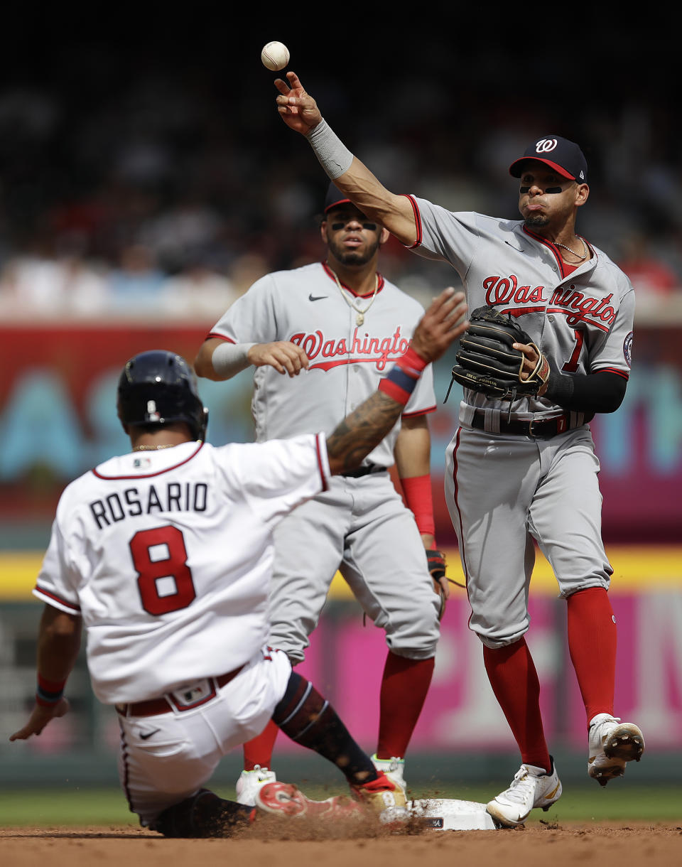 Washington Nationals' Cesar Hernandez, right, throws over Atlanta Braves' Eddie Rosario (8) to complete a double play in the second inning of a baseball game Saturday, July 9, 2022, in Atlanta. Braves' Orlando Arcia was out at first base. (AP Photo/Ben Margot)