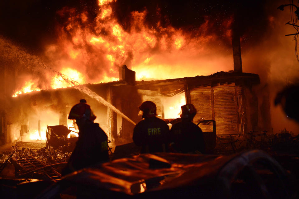 In this Wednesday, Feb. 20, 2019, photo, firefighters try to douse a fire in Dhaka, Bangladesh. A devastating fire raced through at least five buildings in an old part of Bangladesh's capital and killed scores of people. (AP Photo/Mahmud Hossain Opu)