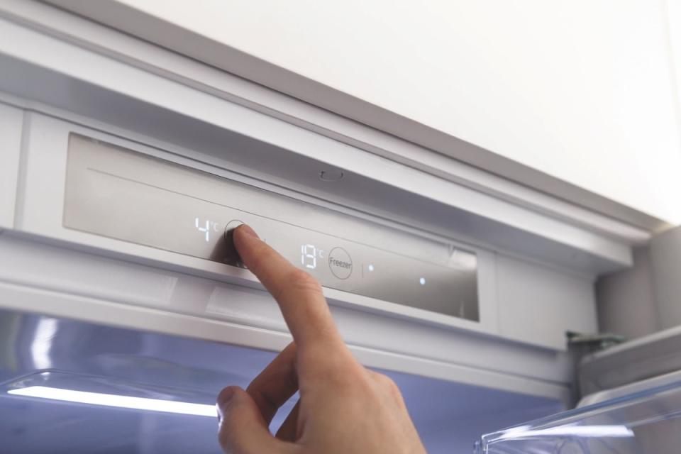 Hand setting a temperature of a refrigerator in degrees Celcius