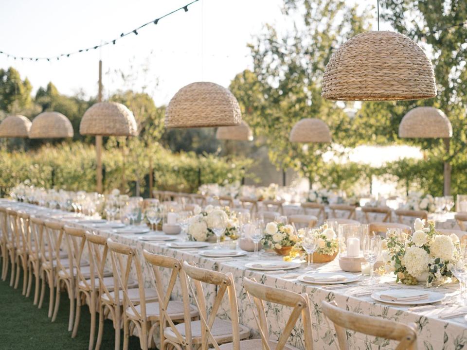 An outdoor wedding with long tables and hanging lights.