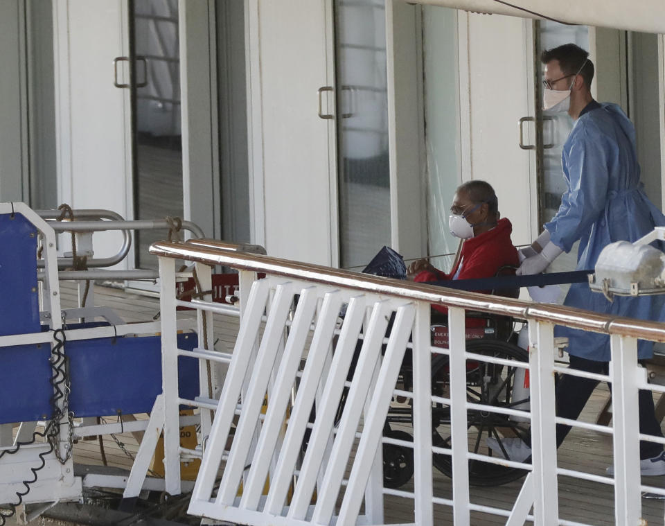 A person in a wheelchair is taken off the cruise ship Rotterdam after docking at Port Everglades during the new coronavirus pandemic, Thursday, April 2, 2020, in Fort Lauderdale, Fla. Those passengers that are fit for travel in accordance with guidelines from the U.S. Centers for Disease Control will be permitted to disembark. (AP Photo/Wilfredo Lee)