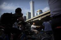 People wait cross the street in a crosswalk in the central business district in Beijing, Friday, May 24, 2019. Stepping up a propaganda offensive against Washington, China's state media on Friday accused the U.S. of seeking to "colonize global business" by targeting telecom equipment giant Huawei and other Chinese companies. (AP Photo/Mark Schiefelbein)