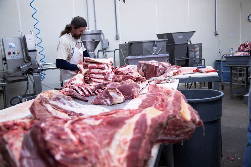 FILE PHOTO: Employee cuts fresh beef meat into large pieces at a meat processing plant in Indiana