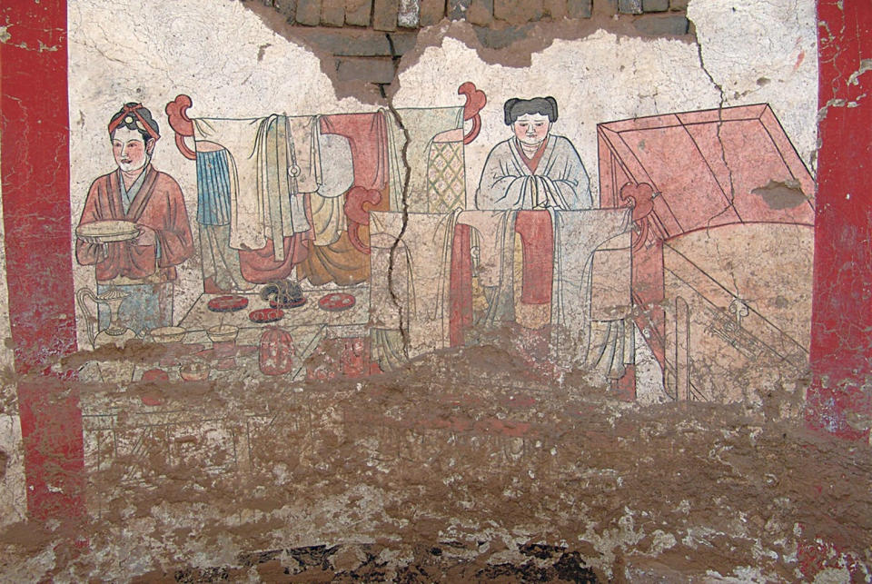 The murals on the west wall of the 1,000-year-old tomb depict articles of clothing as well as two servants. <cite>Courtesy of Chinese Cultural Relics</cite>
