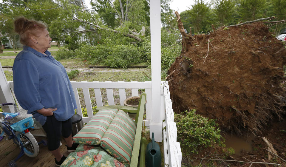 Sandra Cotten of Flora, Miss., looks at her uprooted 100-year old oak tree that now lies across her yard and two streets, Sunday, April 14, 2019. Cotten recalled hearing a loud "swosh" as the massive oak fell next to her house in Saturday's severe weather. She lamented the tree's loss for the summer shade it provided. The storm was one of several that hit the state. (AP Photo/Rogelio V. Solis)