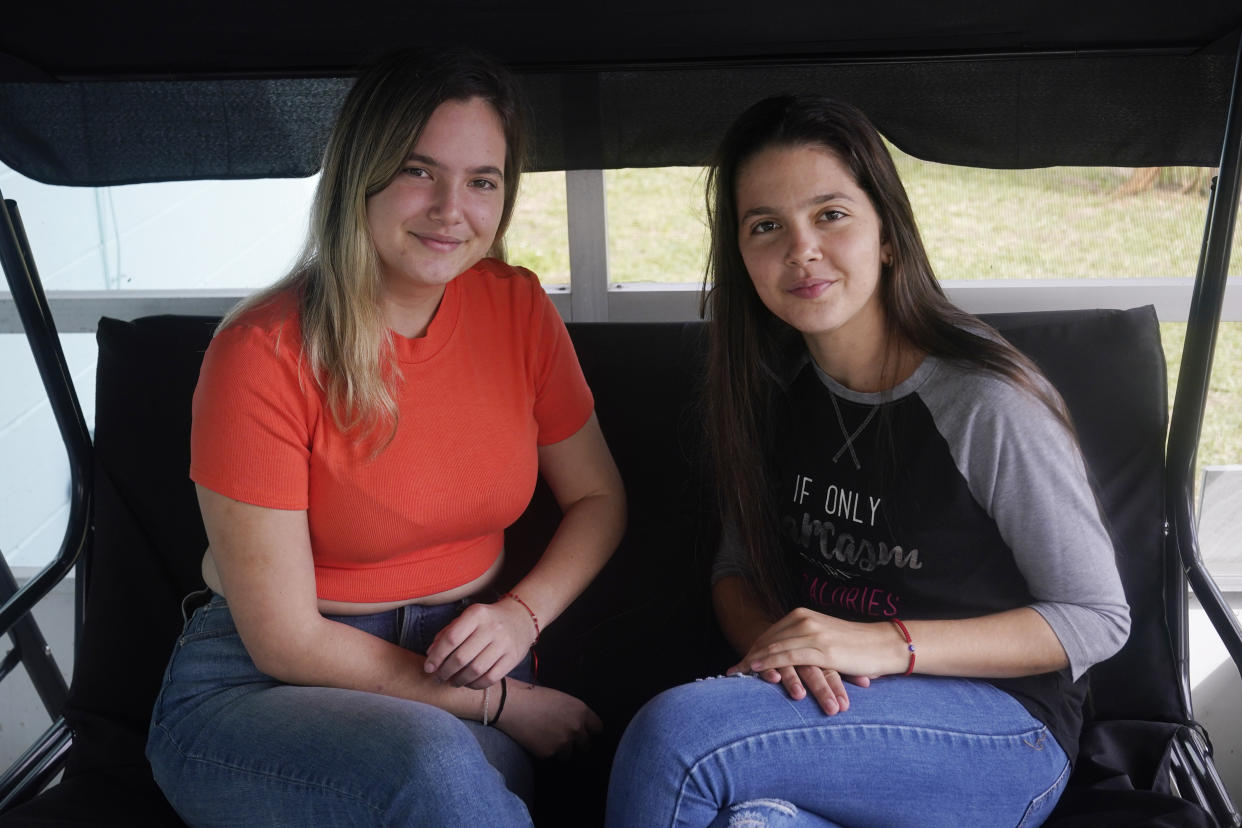 Merlyn Rolo Gonzalez, left, and her sister Melanie sit on the porch of a family friend's home in Daytona, Florida, Wednesday, Jan. 4, 2023. Days earlier, they crossed the U.S.-Mexico border. (AP Photo/Marta Lavandier)