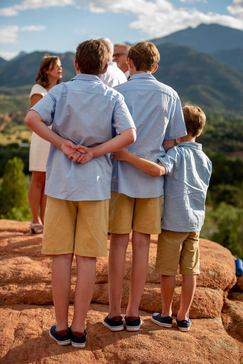 Three sons watch their mother and father get married with mountains in the background.