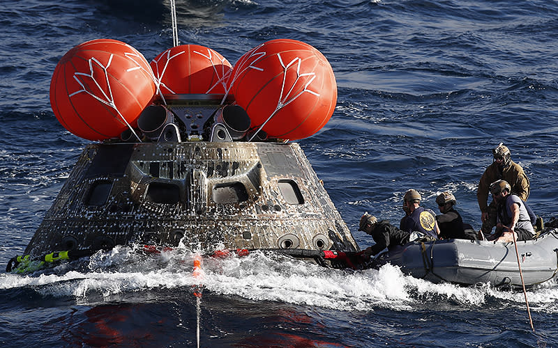 U.S. Navy divers attach winch cables to NASA’s Orion capsule after being successfully secured off the coast of Baja California, Mexico, on Dec. 11. The 26-day Artemis I mission took the Orion spacecraft to the moon and back to complete a historic flight. <em>Caroline Brehman/Pool/UPI</em>