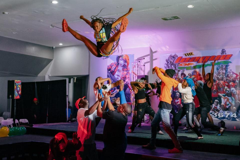 A girl flying through the air, tossed by dancers below her.