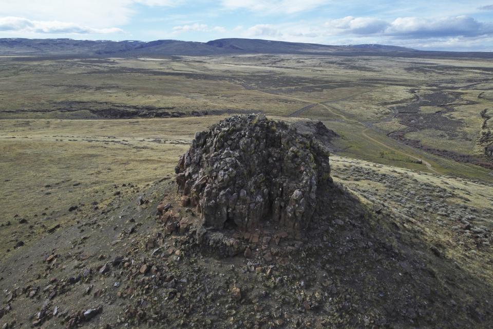 Sentinel Rock stands near a massacre site which juts above sagebrush and high grass used by roaming cattle herd on April 24, 2023, near Orovada, Nev. The Biden administration says the mine will produce battery material needed to meet the administration's goal that half of all new vehicle sales are electric by 2030. But Native American tribes and environmentalists say the open-pit mine at Thacker Pass will harm wildlife habitats, degrade groundwater and pollute the air in a remote region dotted with sagebrush. (AP Photo/Rick Bowmer)