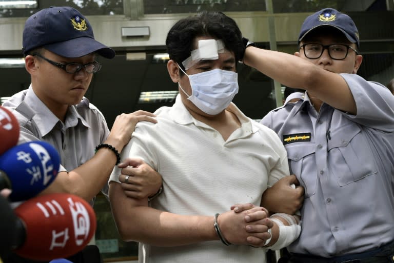 A suspect identified only by his family name Lu (C), is escorted by policemen at a local police bureau in Taipei on August 18, 2017, after he was suspected of slashing a police guard with a Samurai sword at the Presidential Palace