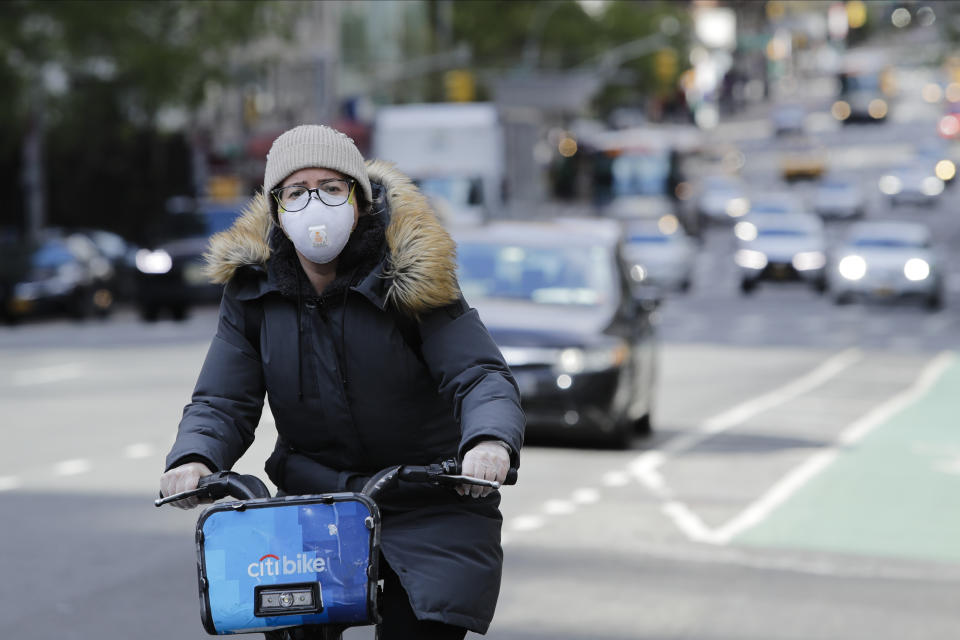 A woman wearing a mask rides a bicycle along second avenue Thursday, April 16, 2020, in New York. (AP Photo/Frank Franklin II)