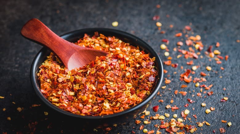 red pepper flakes with wooden spoon