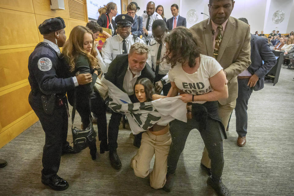 Climate protestors are removed after interrupting a speech by Federal Reserve Chairman Jerome Powell at the 24th Jacques Polak Research Conference at the International Monetary Fund on Thursday, Nov. 9, 2023 in Washington. (AP Photo/Mark Schiefelbein)