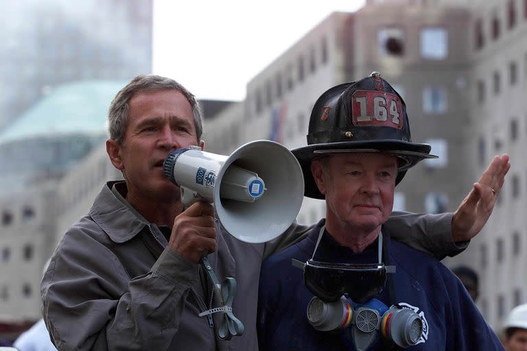 El presidente estadounidense George W. Bush (izq.) Habla junto al bombero retirado Bob beckwith, de 69 años, a voluntarios y bomberos mientras examina los daños en el sitio del World Trade Centerl el 14 de septiembre de 2001 en Nueva York