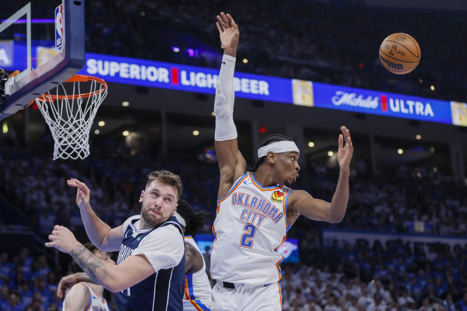 Oklahoma City Thunder guard Shai Gilgeous-Alexander (2) and Dallas Mavericks guard Luka Doncic look on while attempting a rebound during the first half of Game 1 of an NBA basketball second-round playoff series, Tuesday, May 7, 2024, in Oklahoma City. (AP Photo/Nate Billings)