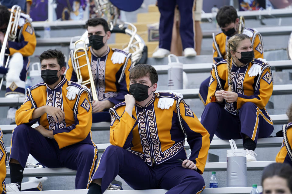 FILE - In this Sept. 26, 2020, file photo, members of the LSU marching band, wearing mask, sit socially distanced from one another due to COVID-19 restrictions before an NCAA college football game between the LSU and the Mississippi State in Baton Rouge, La. Louisiana State University students will have to wear masks in classrooms and at campus events this fall to help fight the spread of COVID-19, but won't have to be vaccinated to return to school, university officials announced Wednesday, Aug. 4, 2021. (AP Photo/Gerald Herbert, File)