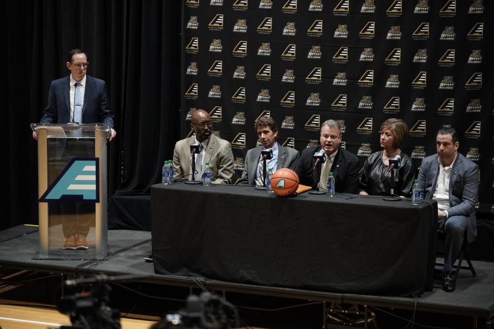 Bryant assistant athletic director for communication Tristan Hobbes speaks during Wednesday's press conference at Bryant's Chace Center. Seated, from left, are America East commissioner Brad Walker, Bryant president Ross Gittell, Bryant athletic director Bill Smith, Bryant women’s basketball coach Mary Burke, Bryant men’s basketball coach Jared Grasso.