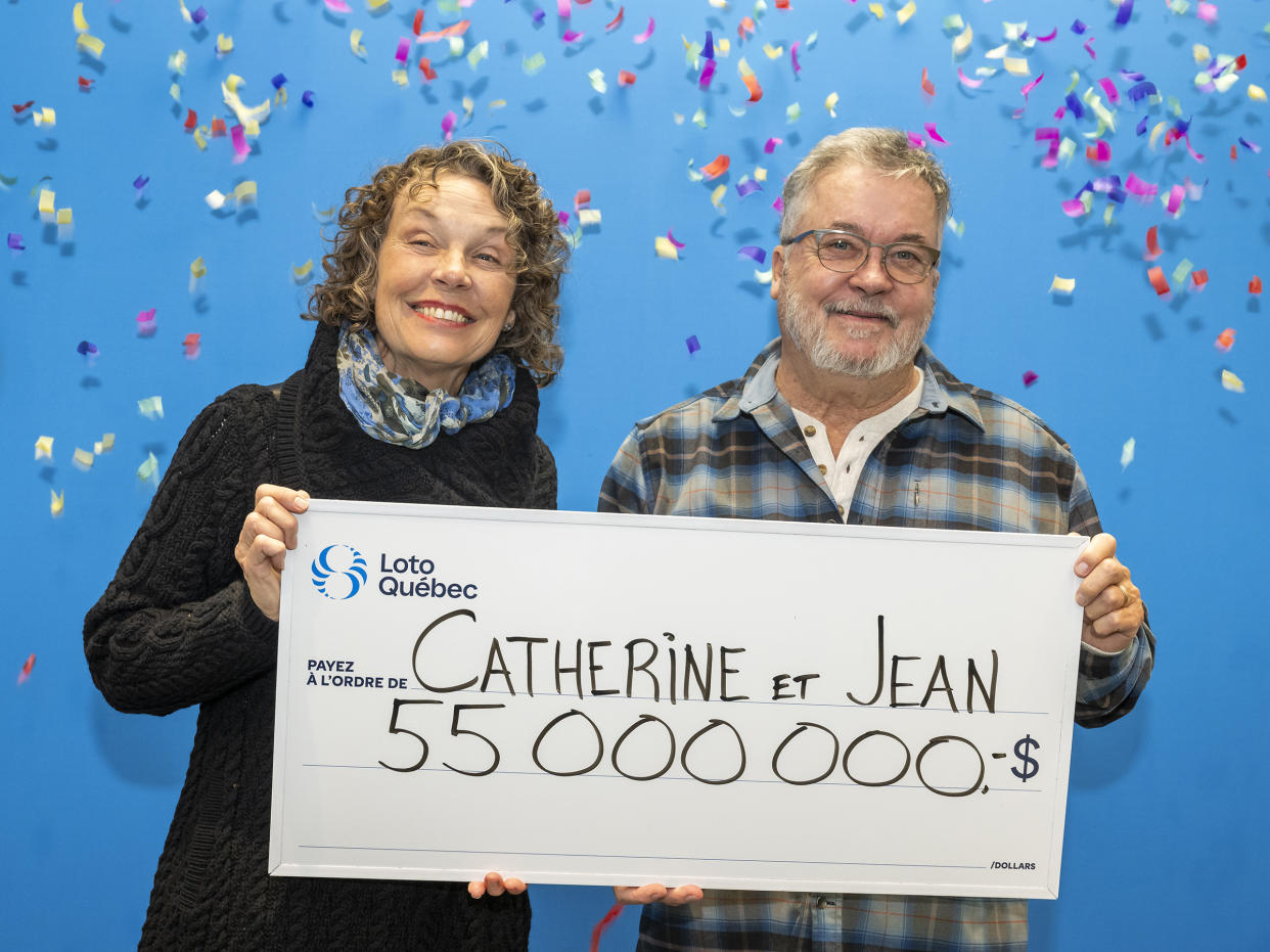 Quebec couple holding a $55 million Loto Quebec cheque. 