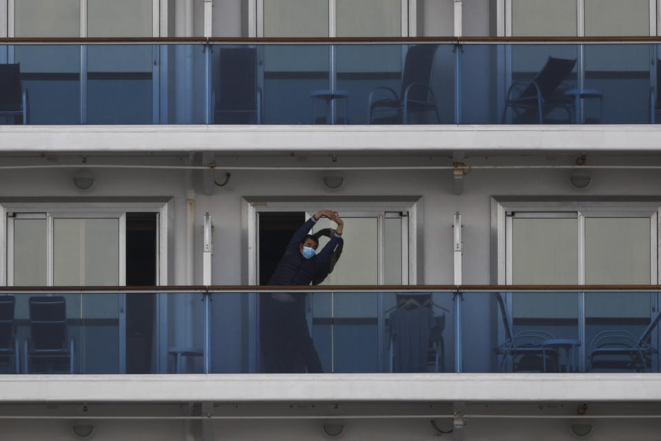 A quarantined passenger on the Diamond Princess cruise ship stretches on the balcony of his cabin Saturday, Feb. 15, 2020, in Yokohama, near Tokyo. A viral outbreak that began in China has infected more than 67,000 people globally. The World Health Organization has named the illness COVID-19, referring to its origin late last year and the coronavirus that causes it. (AP Photo/Jae C. Hong)