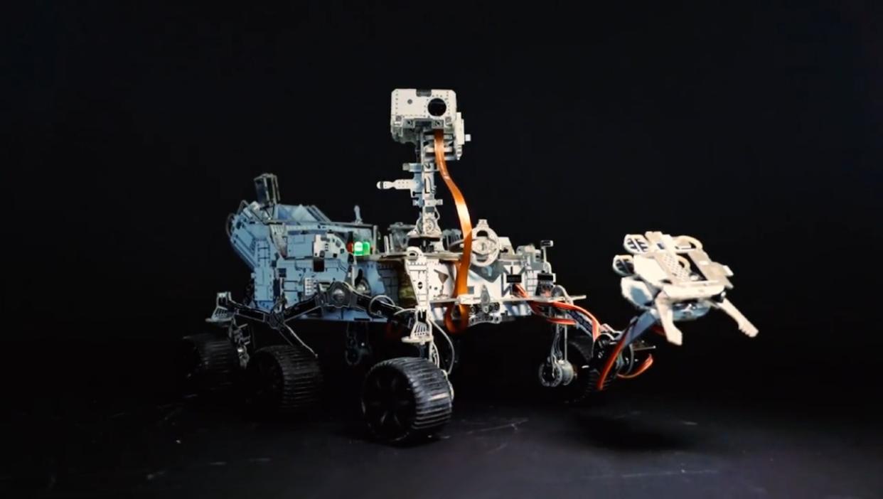  A four-wheeled robot with a robotic arm. 