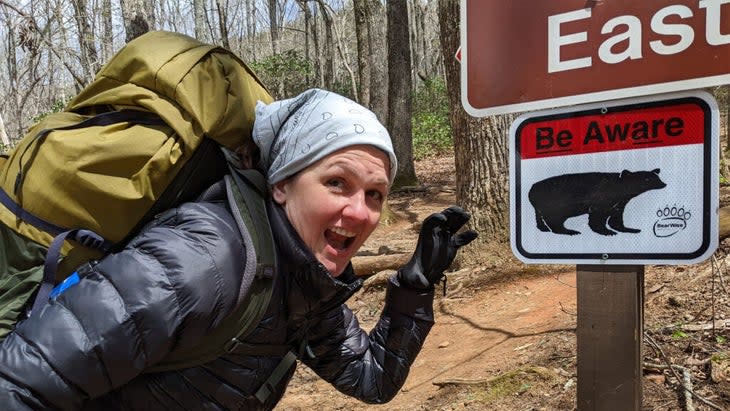 Woman hiker on the Appalachian trail near a sign for Springer Mountain