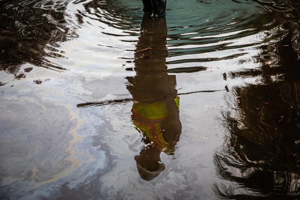 A Public Works Department worker holding a hoe is reflected in rain water that did not drain properly on Palmero Street after a storm on Thursday, July 25, 2024, in Corpus Christi, Texas. The Storm Water department is attempting to unclog an underground pipe.