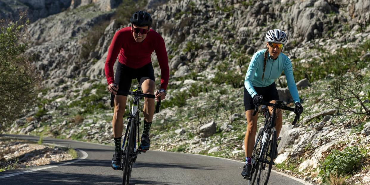 cyclists together riding bicycles on road in front of rocks