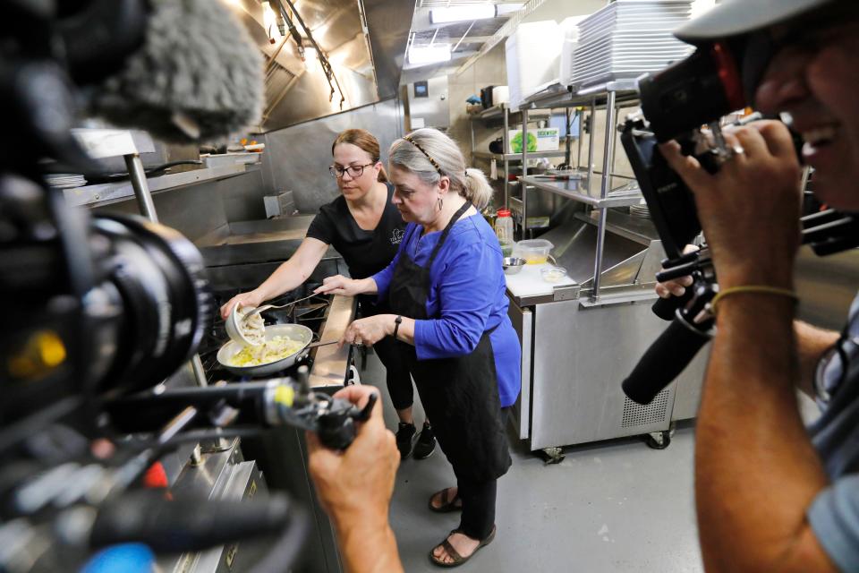Cameraman Charlie Askew, left, and director Dean Camara, film Maria Lawton, right, and Jessica Arruda making Bacalhau à Brás inside of Tia Maria's European Cafe's kitchen in New Bedford for an episode of her PBS show, Maria's Portuguese Table.