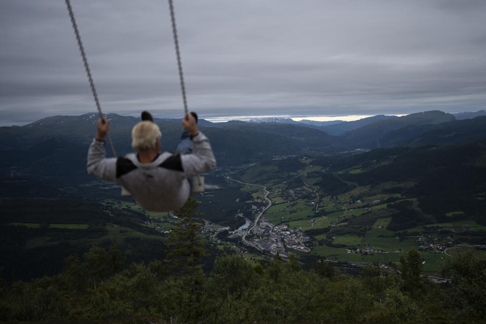 A tourist sits on a swing at a viewing point in Voss, Norway, on Aug. 8, 2022. (AP Photo/Bram Janssen)