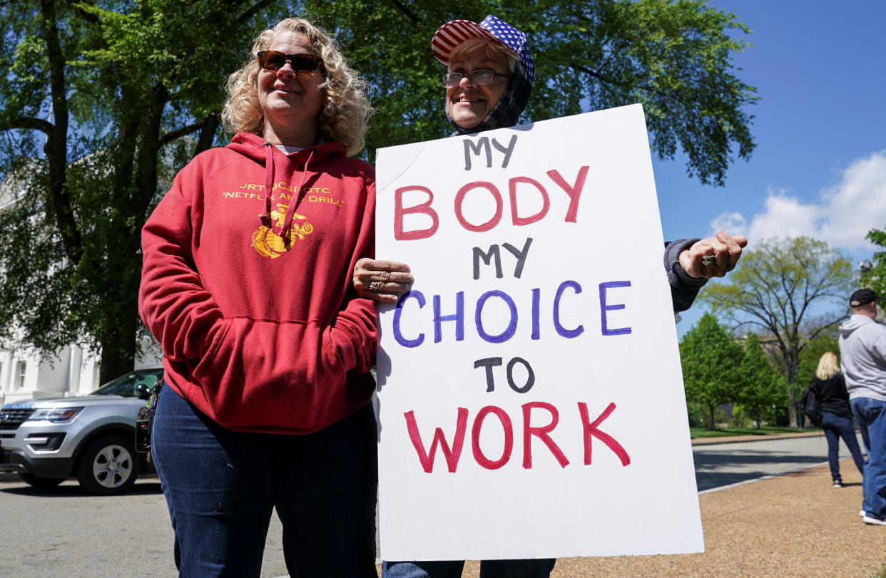 Demonstrators gather with a sign saying 