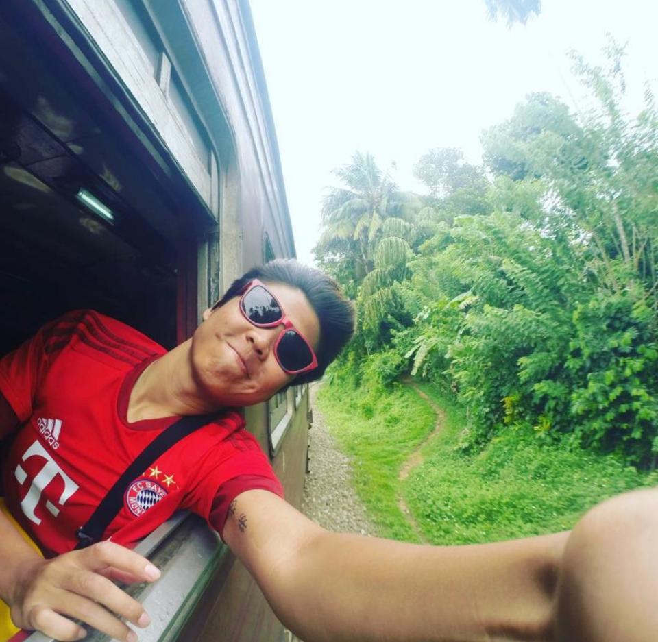 Lady stretching out arm from window taking a selfie on a moving train