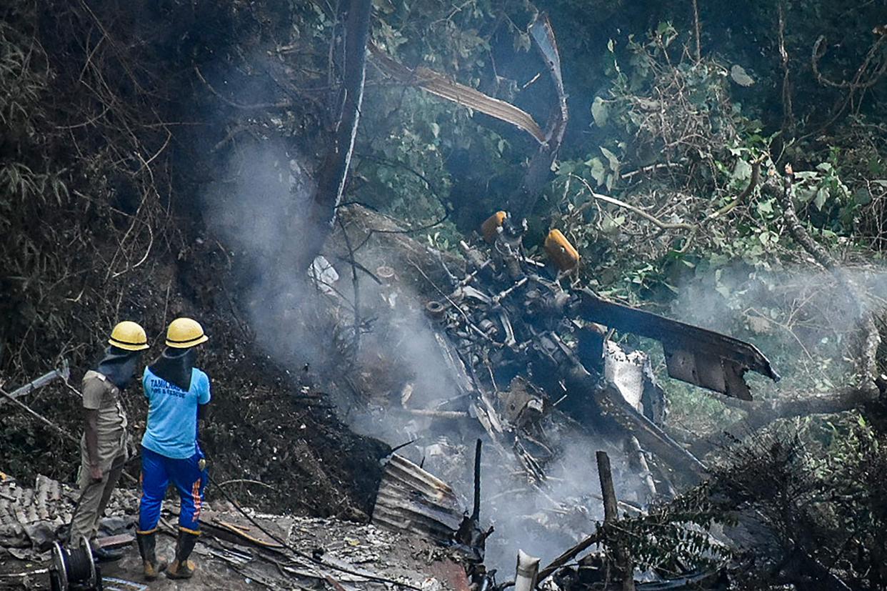 Firemen and rescue workers stand next to the debris of an IAF Mi-17V5 helicopter crash site in Coonoor, Tamil Nadu, on December 8. 