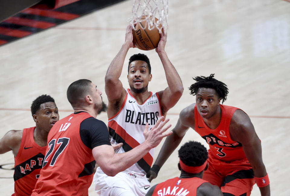 Portland Trail Blazers guard CJ McCollum, center, drives to the basket on Toronto Raptors center Alex Len, left, and forward OG Anunoby, right, during the first half of an NBA basketball game in Portland, Ore., Monday, Jan. 11, 2021. (AP Photo/Steve Dykes)