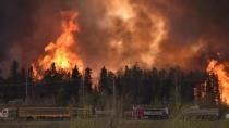 Vehicles travel past a wildfire in Fort McMurray, Alberta on May 3, 2016. CBC News
