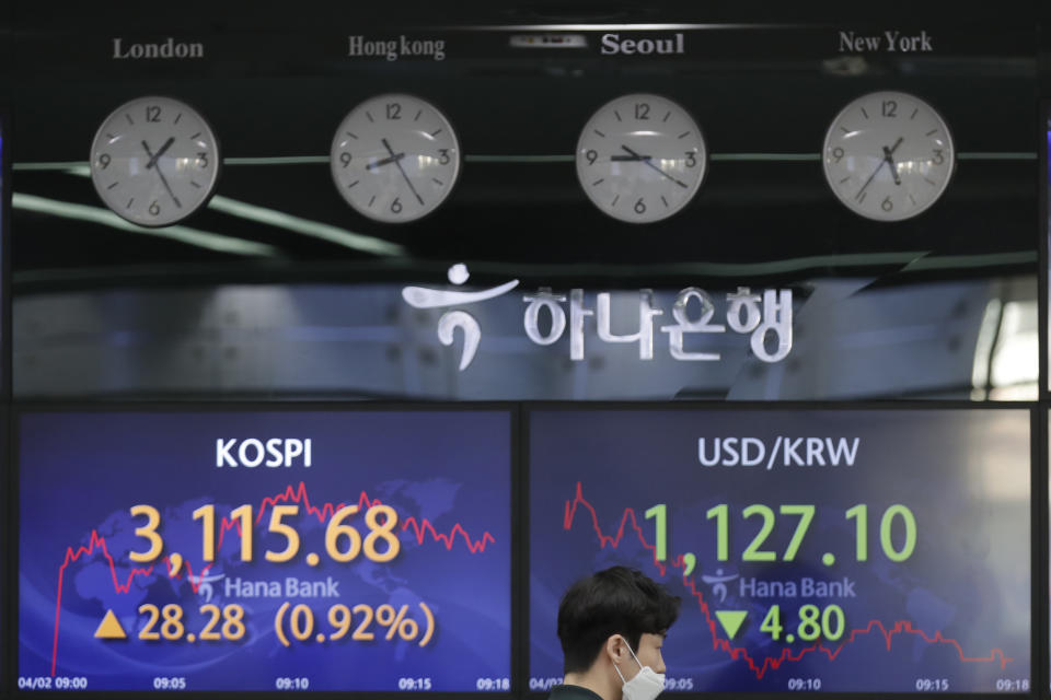 A currency trader walks near the screens showing the Korea Composite Stock Price Index (KOSPI), left, and the foreign exchange rate between U.S. dollar and South Korean won at the foreign exchange dealing room of the KEB Hana Bank headquarters in Seoul, South Korea, Friday, April 2, 2021. Asian shares were higher Friday after a broad rally pushed the S&P 500 past 4,000 points for the first time. (AP Photo/Lee Jin-man)