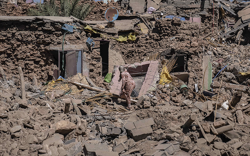 A woman on Sept. 11 tries to recover some possessions from her home, which was destroyed by an earthquake in the village of Tafeghaghte, near Marrakech, Morocco. Rescue crews expanded their efforts Monday as the earthquake’s death toll continued to climb to more than 2,400 and displaced people worried about where to find shelter. <em>Associated Press/Mosa’ab Elshamy</em>