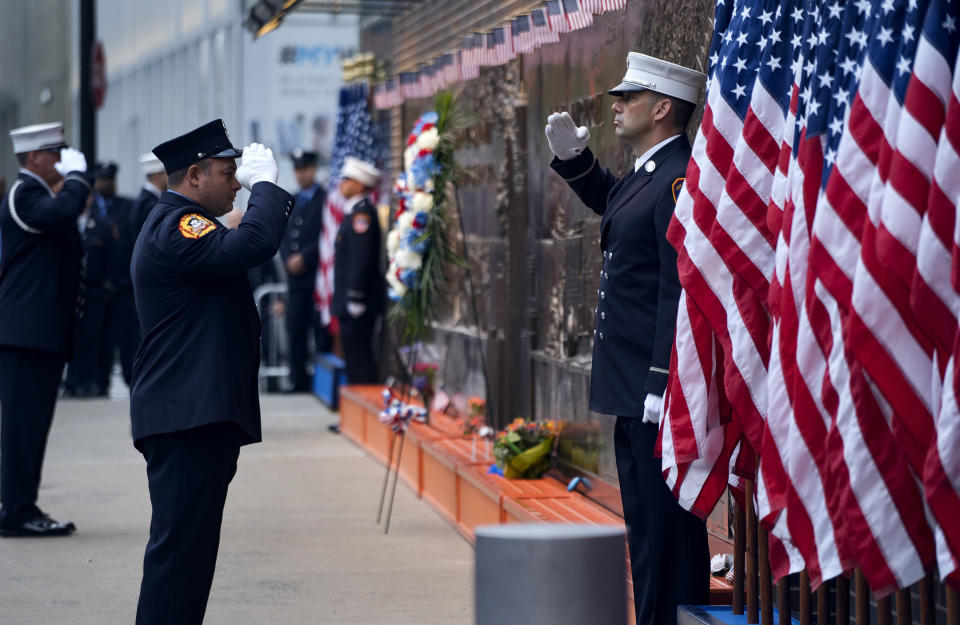 FILE - In this Sept. 11, 2018, file photo, New York City firefighters salute in front of a memorial on the side of a firehouse adjacent to One World Trade Center and the 9/11 Memorial site during ceremonies on the anniversary of 9/11 terrorist attacks in New York. Because of the coronavirus, the Fire Department has urged members to stay away from any of the 2020 observances of the 2001 terror strike that killed nearly the 3,000 people, among them almost 350 firefighters. (AP Photo/Craig Ruttle, File)