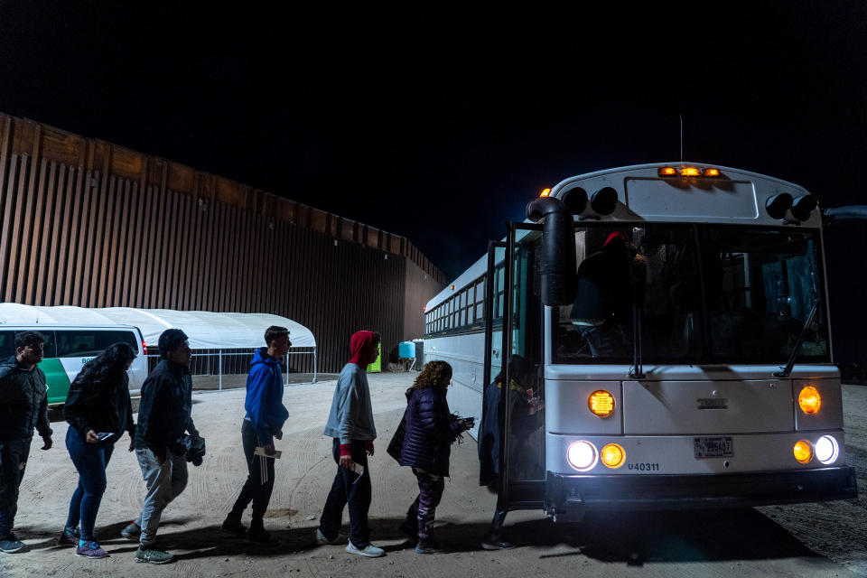 Migrants and asylum seekers board a transport bus after being detained by U.S. Border Patrol agents in Yuma County on Dec. 8, 2022.