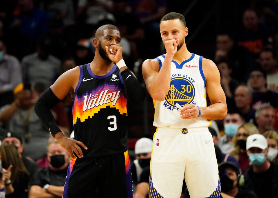 Nov 30, 2021; Phoenix, Arizona, USA; Phoenix Suns guard Chris Paul (3) and Golden State Warriors guard Stephen Curry (30) talk into their hands at Footprint Center.