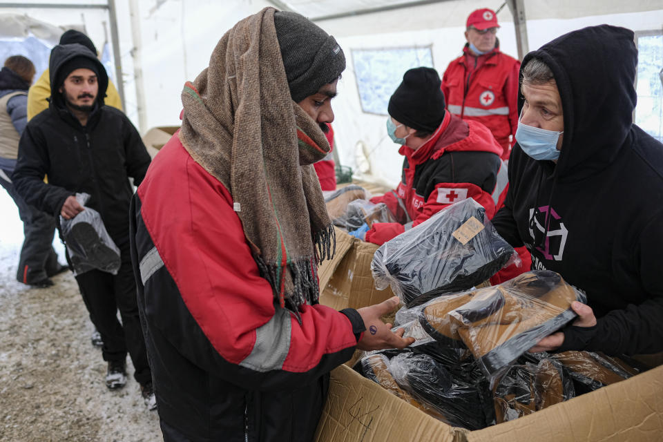 Migrants receive footwear and blankets from a humanitarian organization at the Lipa camp, outside Bihac, Bosnia, Monday, Jan. 11, 2021. Aid workers say migrants staying at a camp in northwestern Bosnia have complained or respiratory and skin diseases after spending days in make-shift tents and containers amid freezing weather and snow blizzards. Most of the hundreds of migrants at the Lipa facility near Bosnia's border with Croatia on Monday have been accommodated in heated military tents following days of uncertainty after a fire gutted most of the camp on Dec. 23. (AP Photo/Kemal Softic)