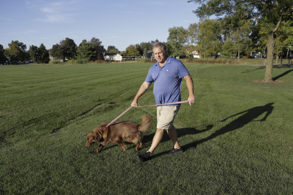 Mark Stenske walks his dog, Leo, as he discusses the impeachment inquiry into President Donald Trump while walking in a park, Wednesday, Oct. 9, 2019, in Fishers, Ind. (AP Photo/Darron Cummings)