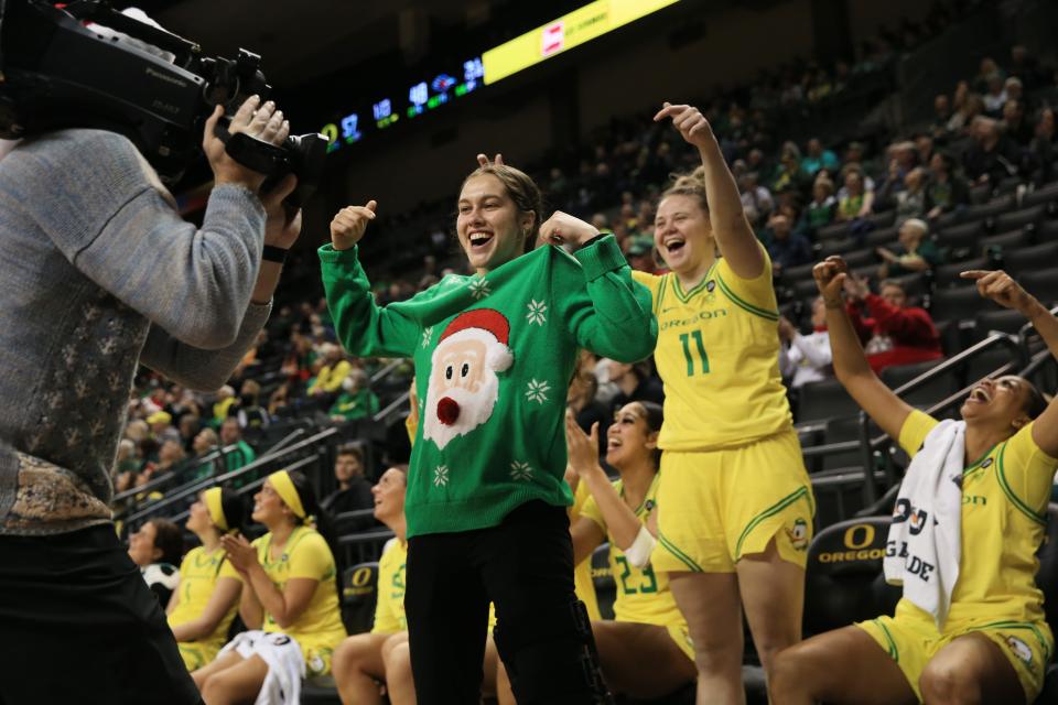 Oregon’s Peyton Scott, center, who was injured early in the season, shows off her ugly Christmas sweater during the game against UTSA at Matthew Knight Arena in Eugene Dec. 17, 2023.