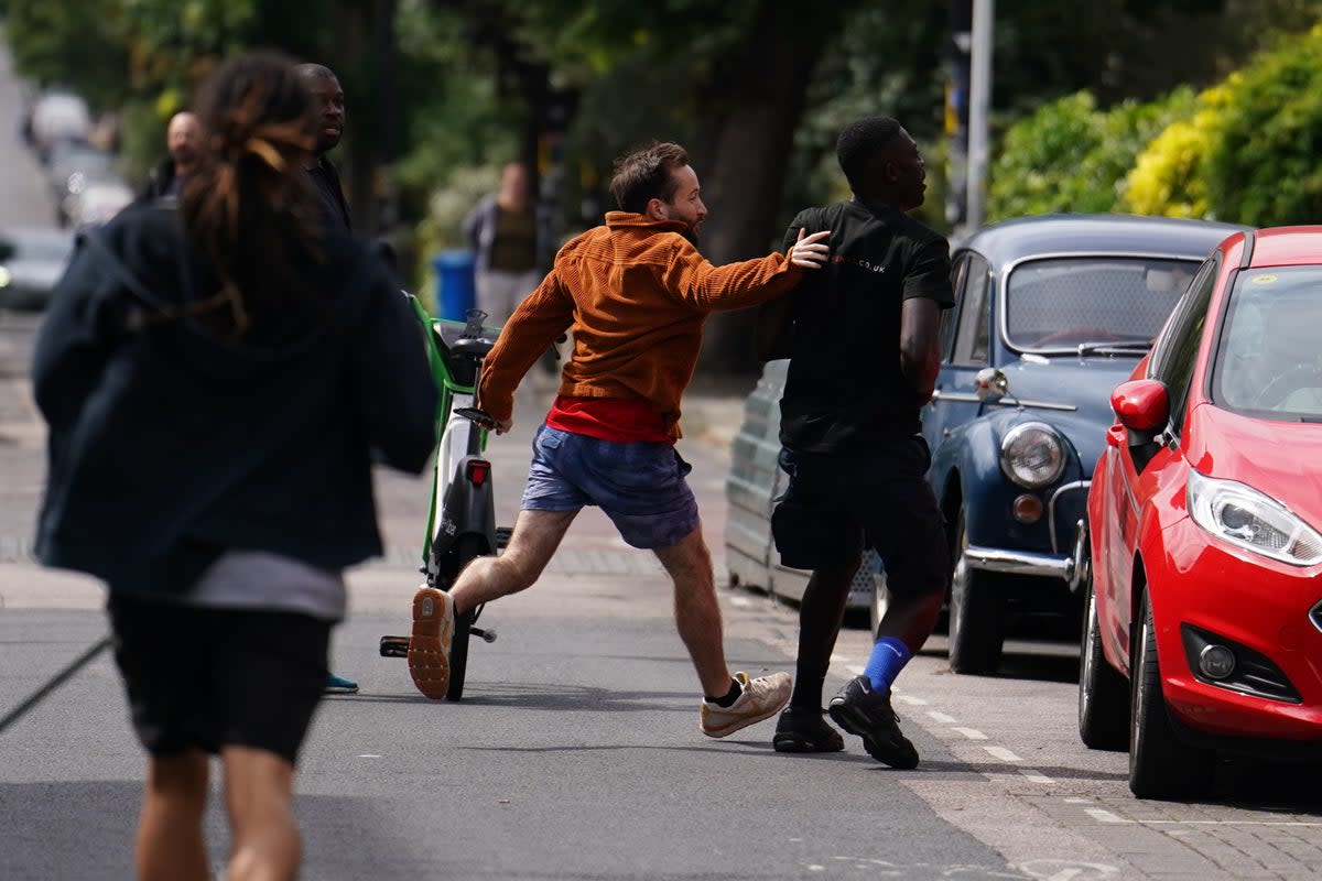 Tom Kellow (orange jacket) chases the people who removed a new artwork by Banksy (Jordan Pettitt/PA Wire)