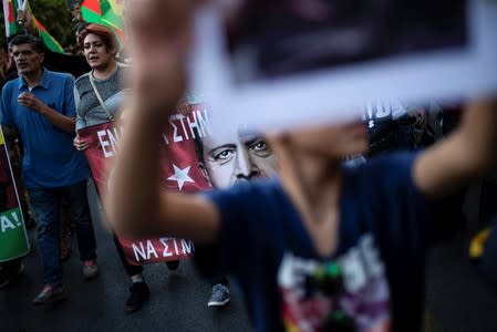 Kurds living in Greece hold a banner depicting Turkish President Tayyip Erdogan during a demonstration against Turkey's military action in northeastern Syria, in Athens