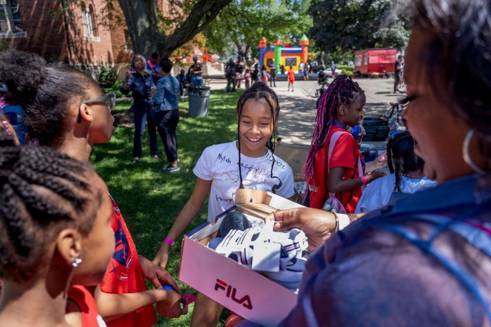 Madalynn Teart, of Detroit, smiles while showing a pair of sandals given to her during the Community Resource Fair at Christ the King Catholic School in Detroit on Aug. 18, 2023.