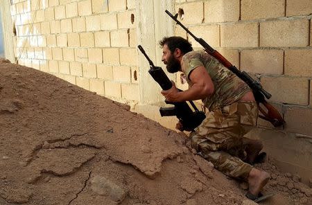 A member of forces loyal to Libya's eastern government carries his weapon during clashes with the Shura Council of Libyan Revolutionaries in Benghazi, Libya April 19, 2016. REUTERS/Stringer