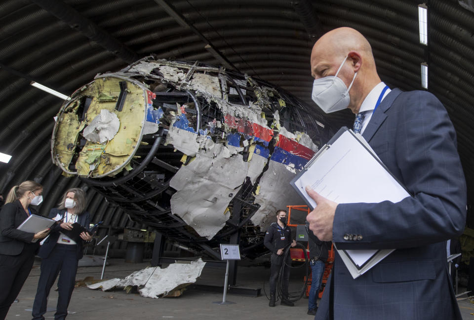 FILE- In this Wednesday, May 26, 2021, file photo Presiding judge Hendrik Steenhuis, right, and other trial judges and lawyers view the reconstructed wreckage of Malaysia Airlines Flight MH17, at the Gilze-Rijen military airbase, southern Netherlands. The trial in absentia in a Dutch courtroom of three Russians and a Ukrainian charged in the downing of Malaysia Airlines flight MH17 in 2014 moves to the merits phase, when judges and lawyers begin assessing evidence. (AP Photo/Peter Dejong, File)